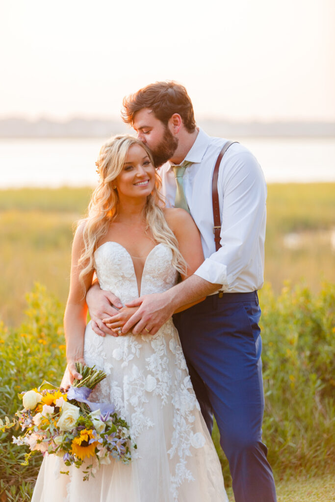 Lowndes Grove wedding groom kisses bride's forehead during sunset portraits