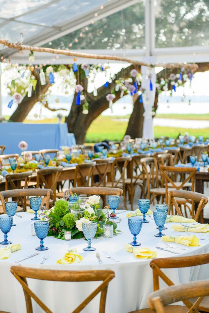 Lowndes Grove wedding summer reception with vintage blue goblets, yellow napkins, moss green centerpieces, and votive candle holders