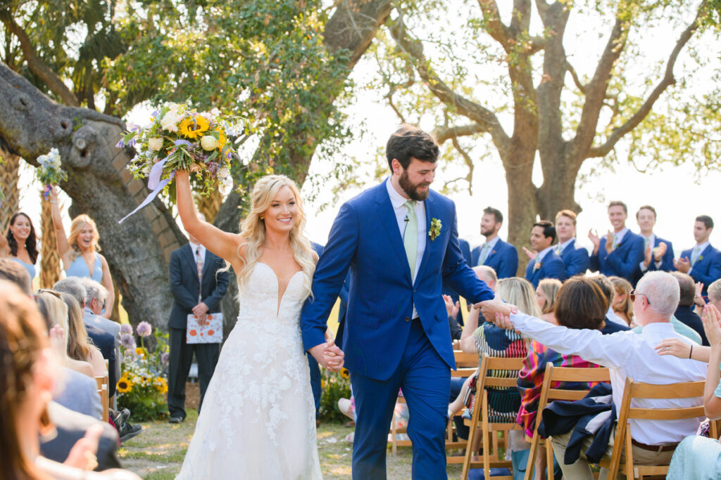 Lowndes Grove ceremony bride and groom walking up aisle with bride holding up bouquet in excitement