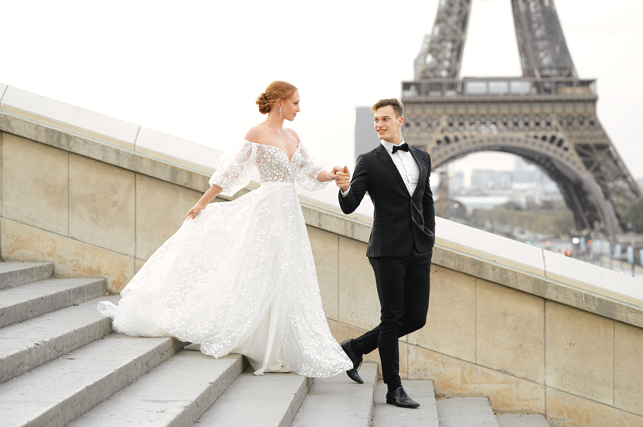 Bride and groom walking in front of Eiffel Tower in Paris France