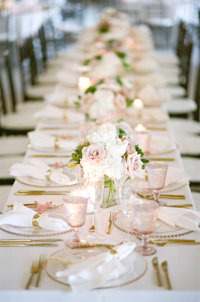 Westin Hilton Head wedding dinner set up with gold trimmed chargers, white and pink rose floral centerpieces and pink drinking glasses