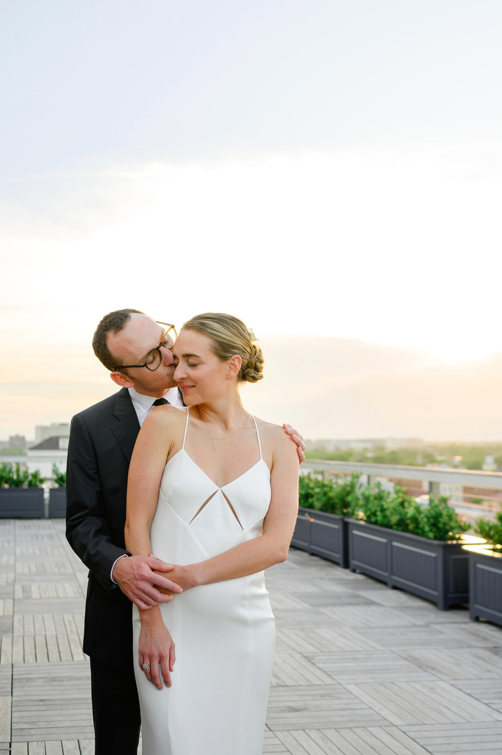 Dewberry Charleston wedding groom kissing bride's cheek during sunset on the rooftop