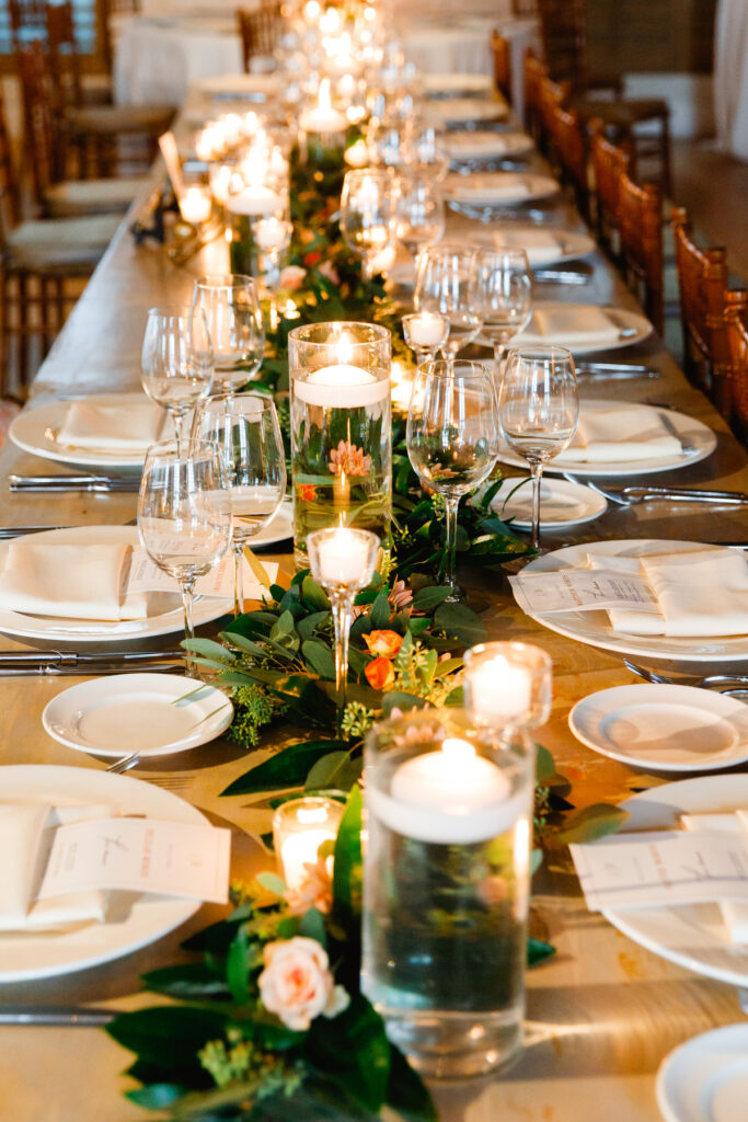 Family style table with floating candles, cascading greenery with orange and pink flowers