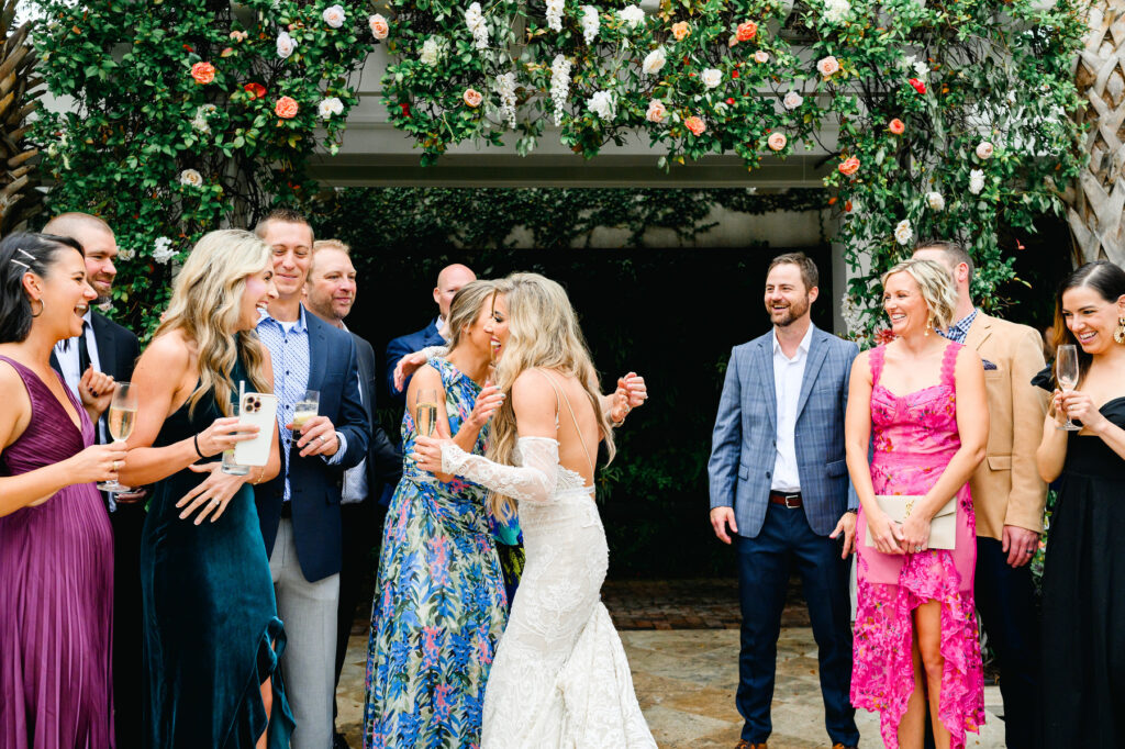 Bride hugs a friend in the courtyard during cocktail hour at a Cannon Green Wedding