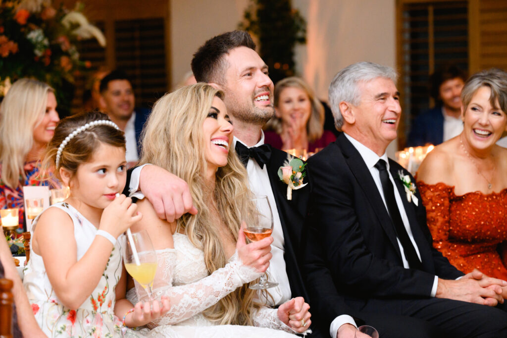 Bride and groom laughing while father of the bride gives a toast during the reception in the Trolley Room at a Cannon Green Wedding