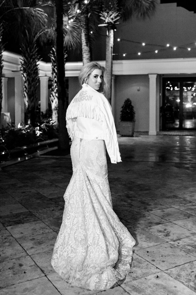 Bride wearing custom Mrs Swanson jacket with fringe in the courtyard at a Cannon Green Wedding