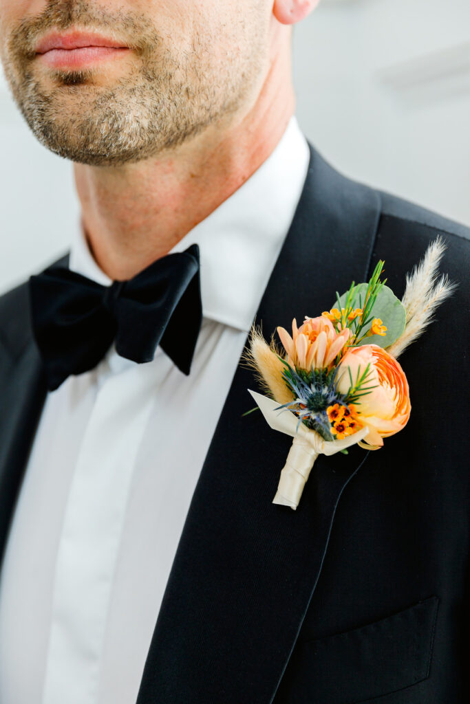 Groom's boutonniere with orange rose and blue flowers