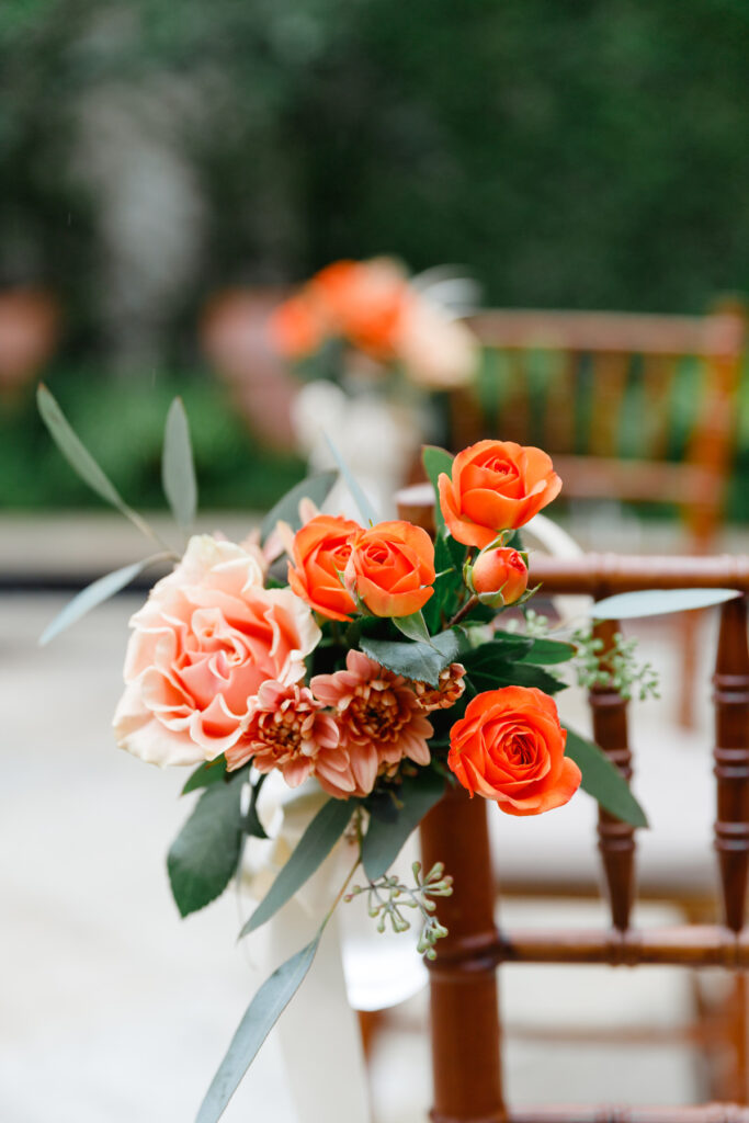 Aisle flower arrangement of orange roses and pink flowers at Cannon Green wedding