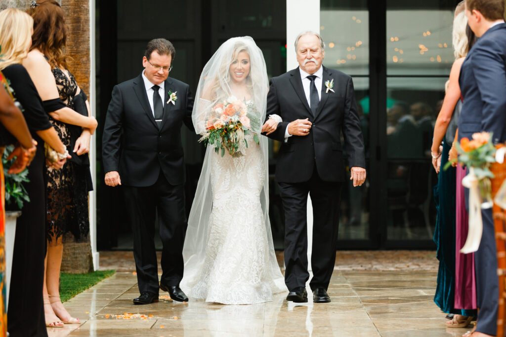 Bride walks down the aisle escorted by her father and step-father at a Cannon Green Wedding