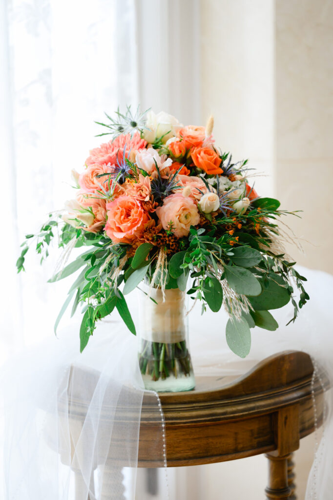 Bridal bouquet with orange and white roses and blue accents