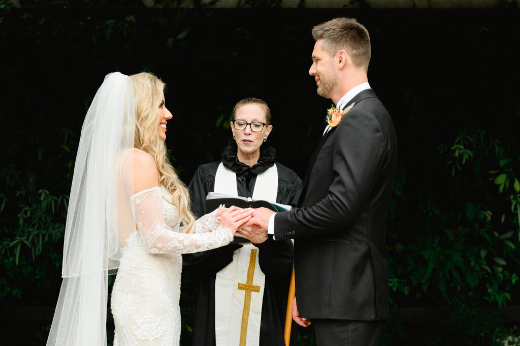 Bride slips ring on groom's finger during ceremony at a Cannon Green Wedding