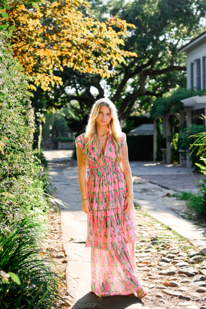 Young woman in pink and green maxi dress in a cobblestone ally downtown Charleston, SC