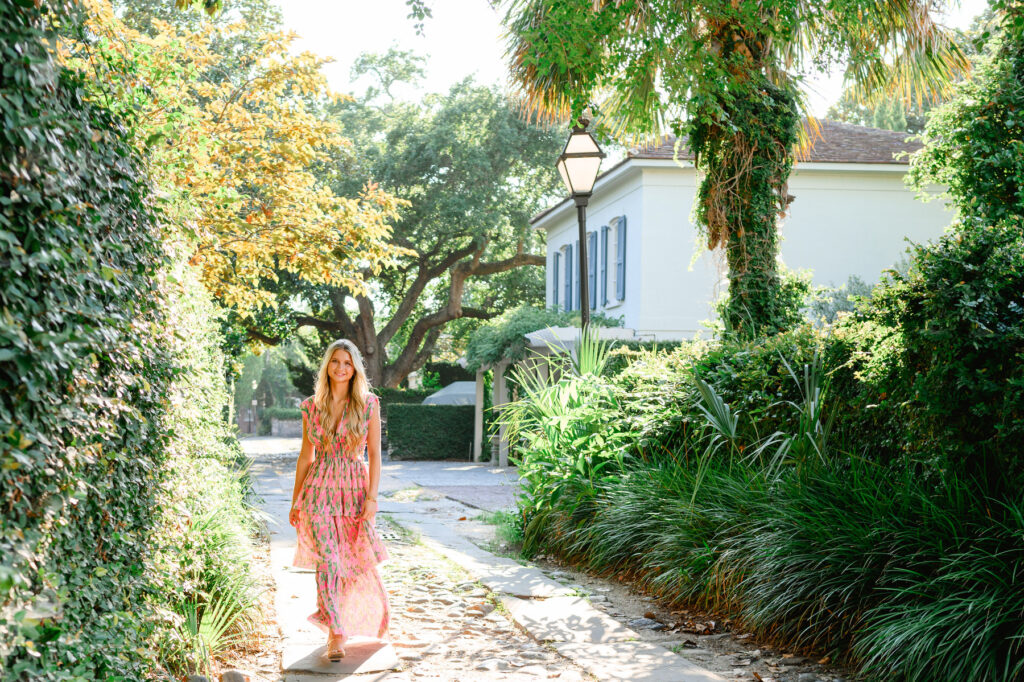 Young woman in pink and green maxi dress in a cobblestone ally downtown Charleston, SC