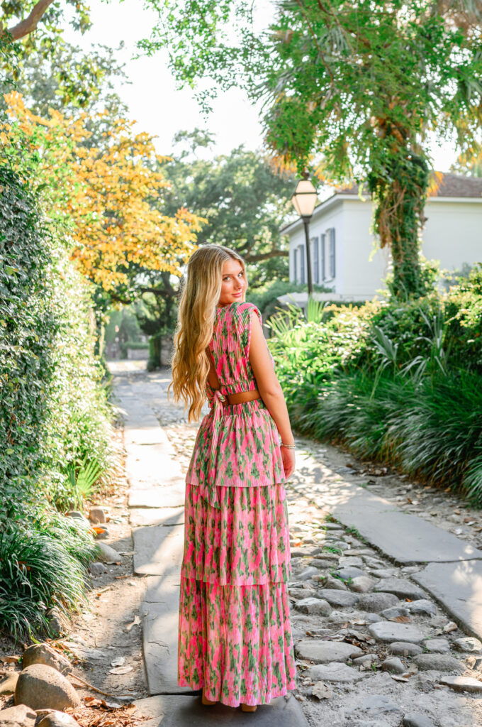 Young woman in pink and green maxi dress in a cobblestone ally downtown Charleston, SC