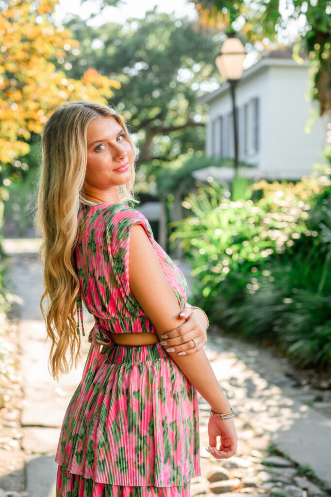 Young woman in pink and green maxi dress in a cobblestone ally downtown Charleston, SC