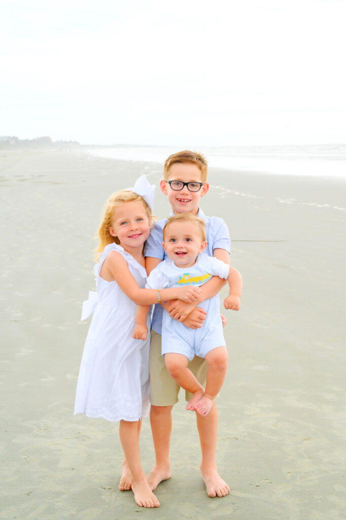 Young siblings hold their baby brother during a Kiawah beach family photo