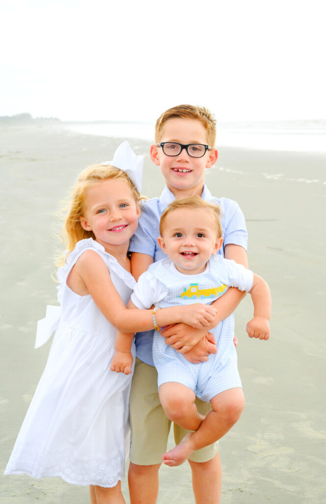 Two siblings hold their baby brother during a Kiawah beach family photo