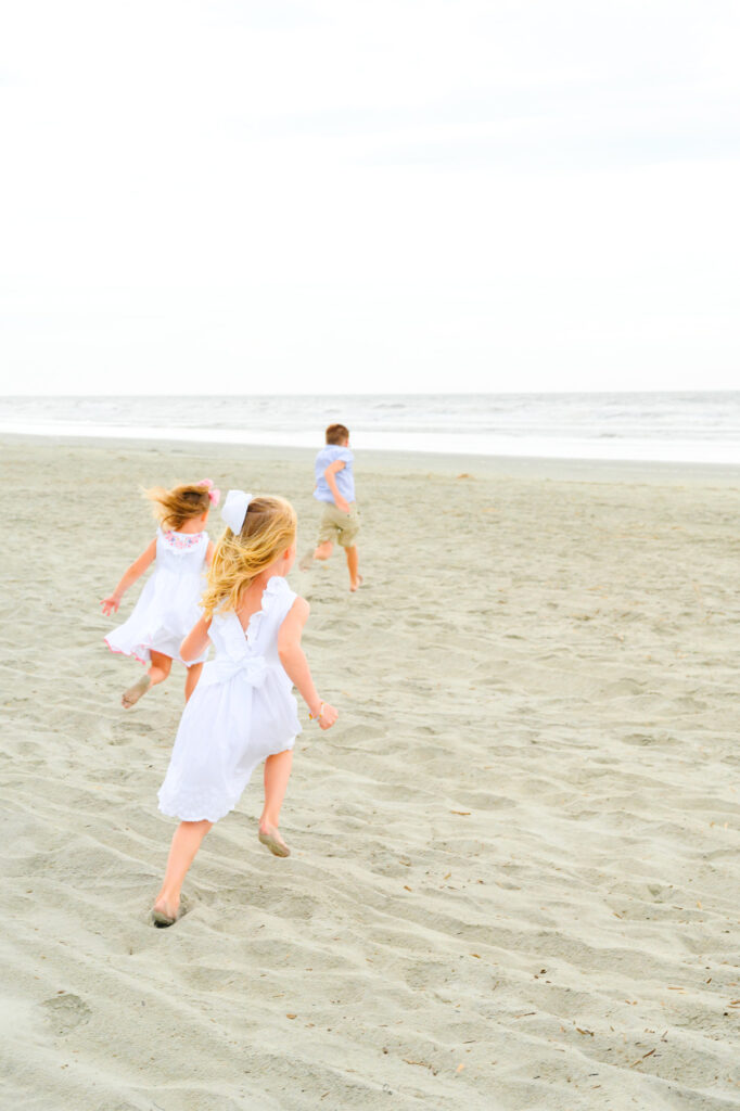 Children run towards the ocean during a Kiawah beach family photo