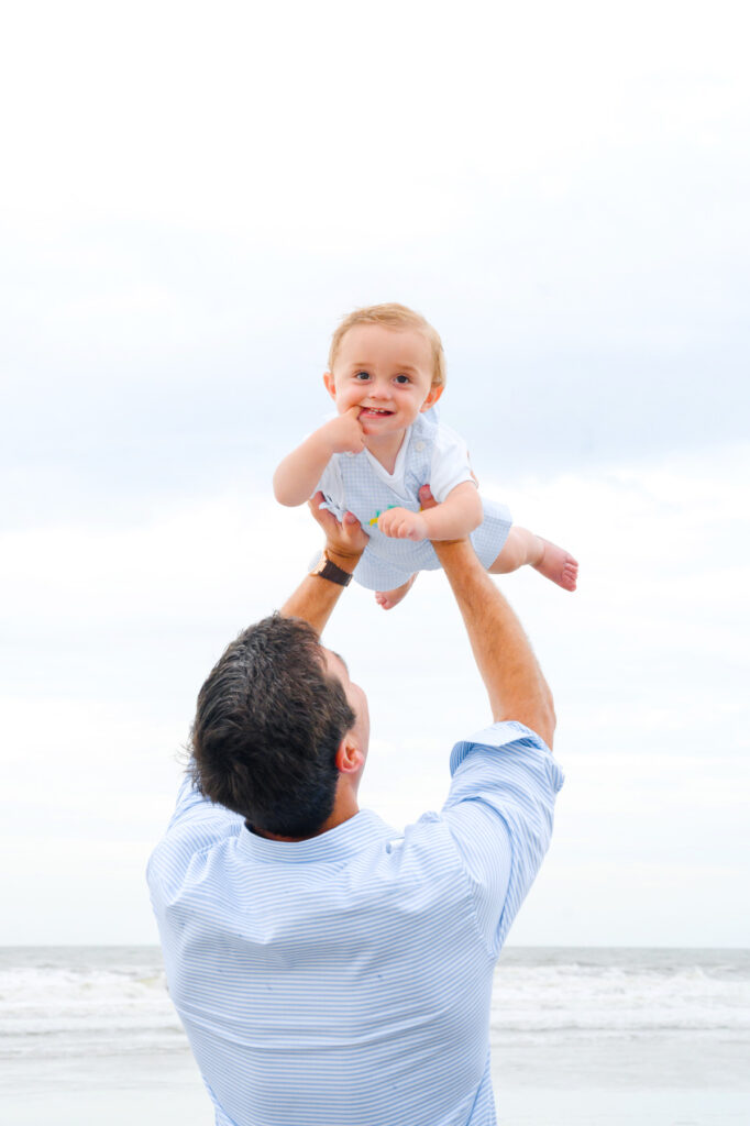 Dad holds baby son in air during Kiawah beach family photo