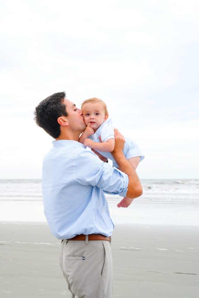 Dad kisses his baby son's cheek during a Kiawah beach family photo