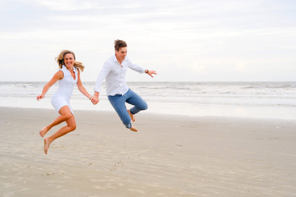 Couple jumps in the air during a Kiawah beach family photo