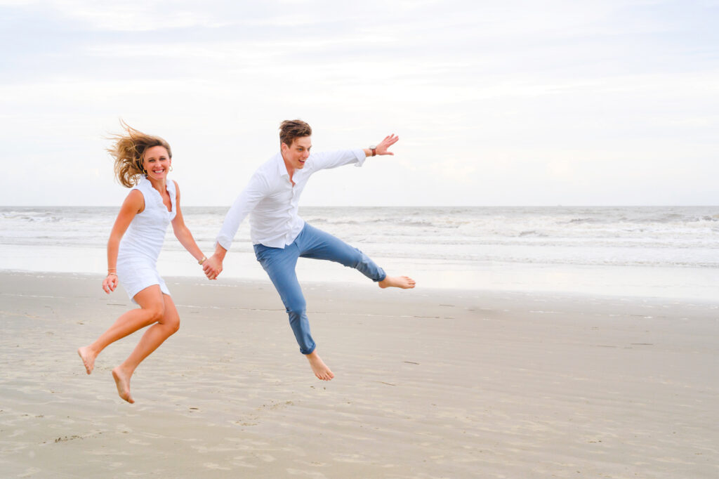 Newlywed couple jump into the air during a Kiawah beach family photo