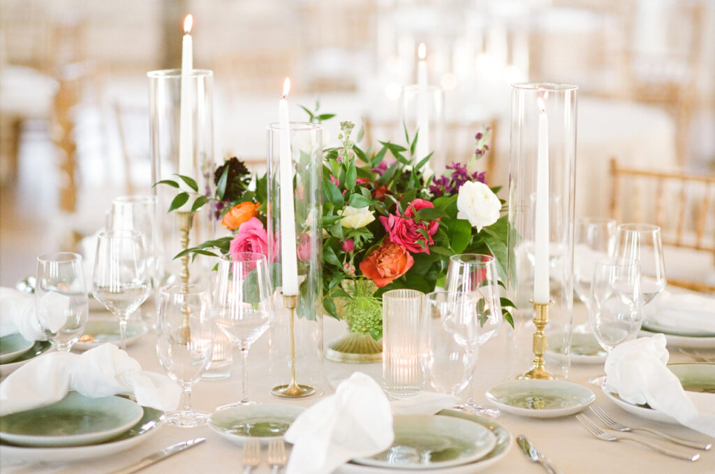 Cedar Room wedding reception floral centerpiece with pink, orange, and white roses with green plate and white napkin place settings