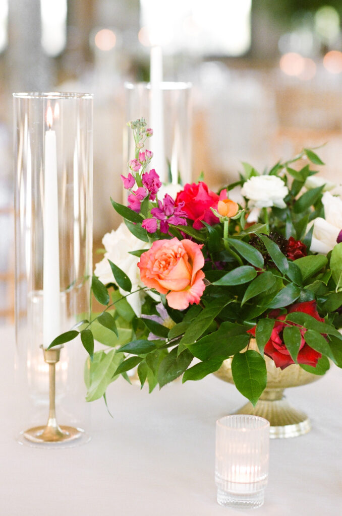 Cedar Room wedding reception floral centerpiece with orange, red, and white roses with white taper candles