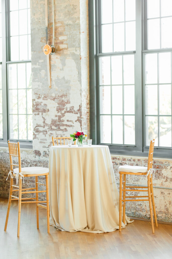 Cedar Room wedding with cocktail table with high chairs and red flowers