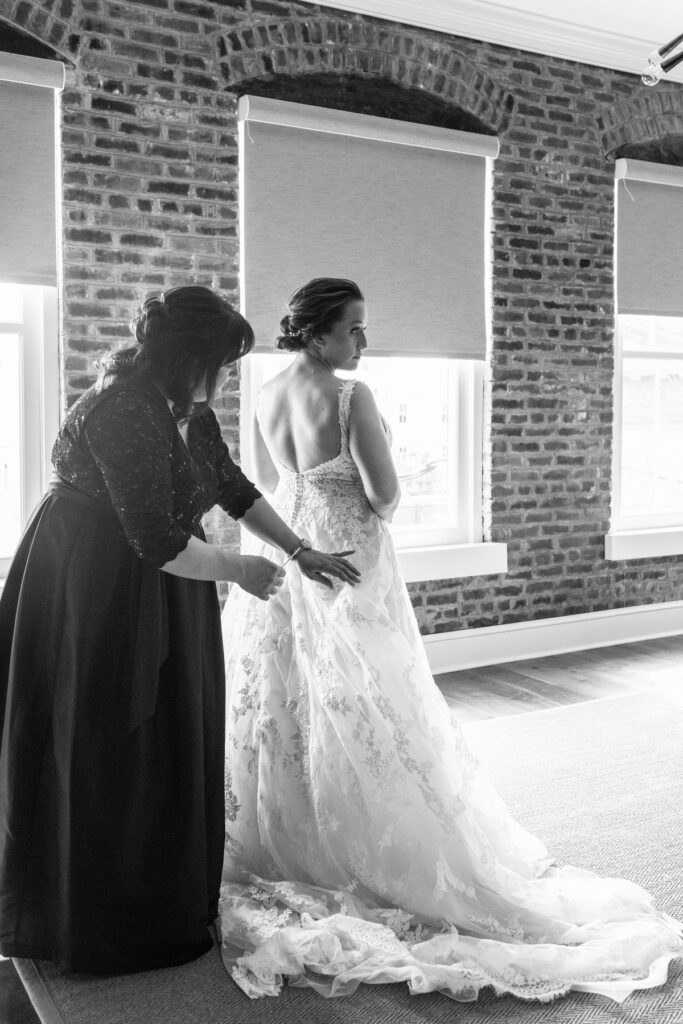 Cedar Room wedding photo of the bride's sister helping the bride get into her gown at the St Philip Suite at Planter's Inn Hotel