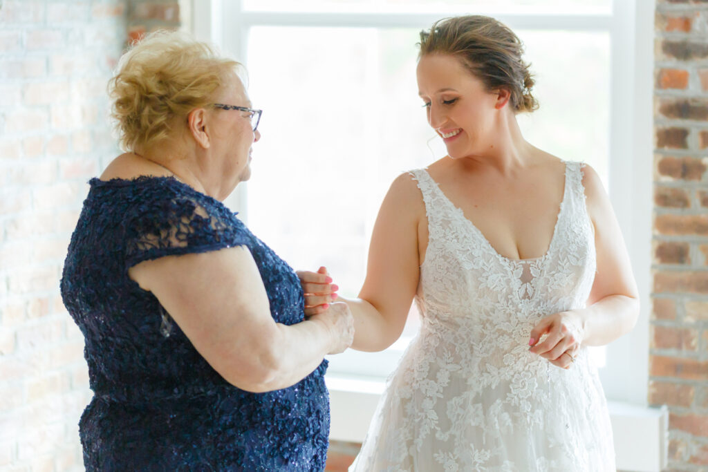 Cedar Room wedding photo of the mother of the bride placing a bracelet on the bride's wrist while getting ready at Planter's Inn