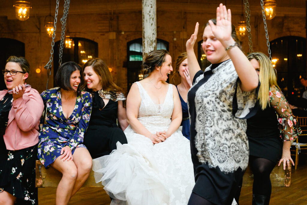 Cedar Room wedding with the bride on a swing at the reception laughing with her friends