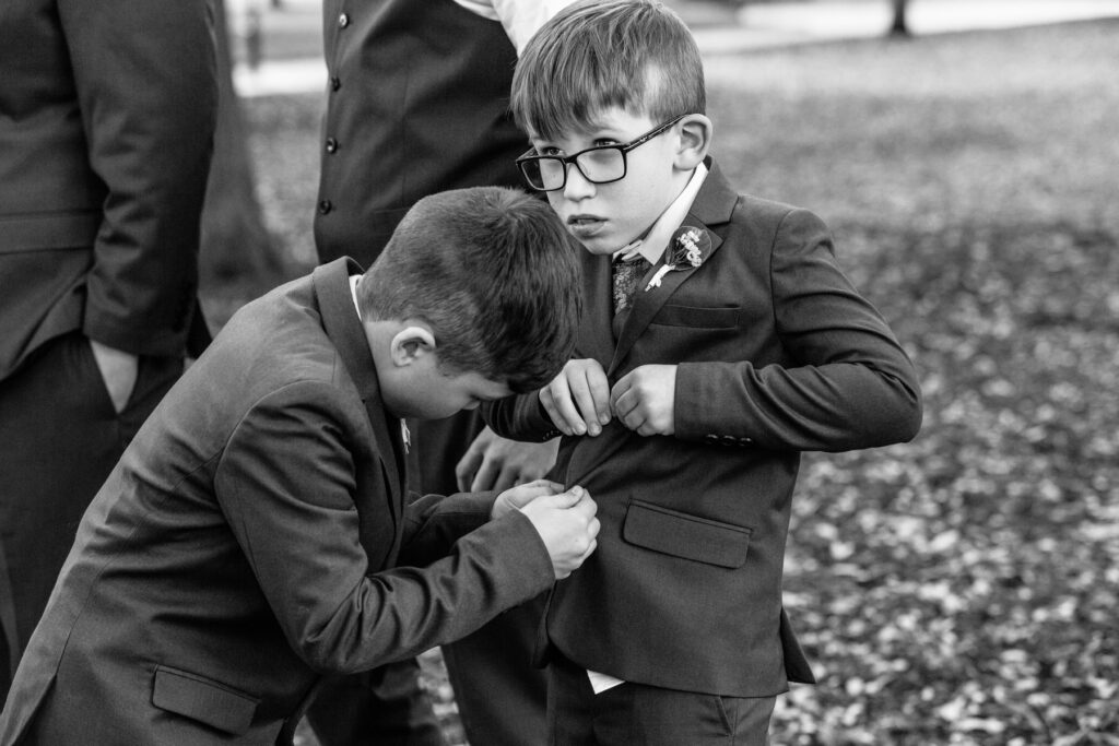 Cedar Room wedding ring bearer helping another boy button his coat