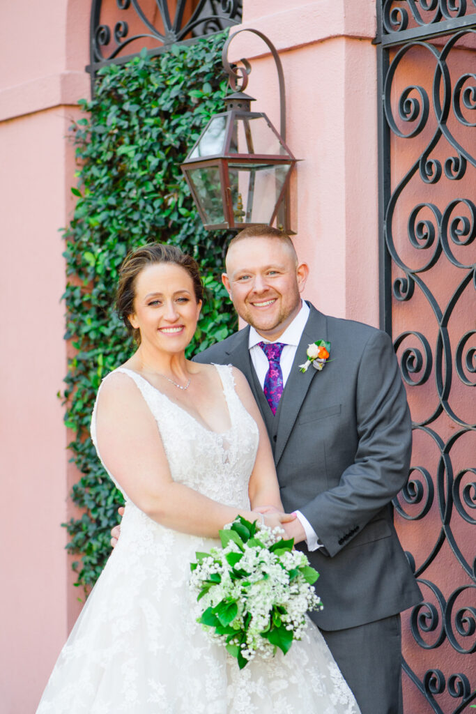 Cedar Room wedding portrait of bride and groom in front of pink house on Rainbow Row