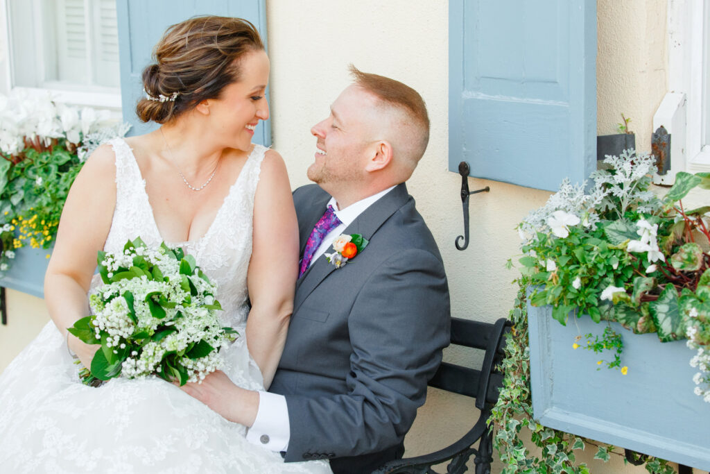 Cedar Room wedding portrait of bride and groom sitting on a bench on Rainbow Row