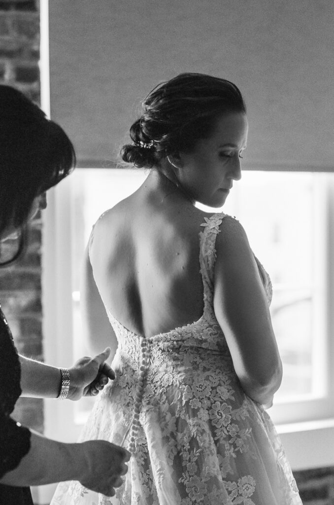 Cedar Room wedding photo of the bride's sister helping the bride get into her gown at the St Philip Suite at Planter's Inn Hotel