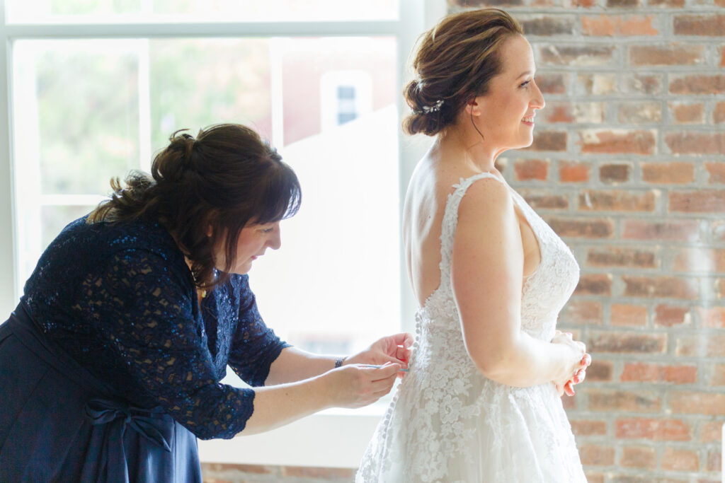 Cedar Room wedding photo of the bride's sister helping the bride get into her gown at the St Philip Suite at Planter's Inn Hotel