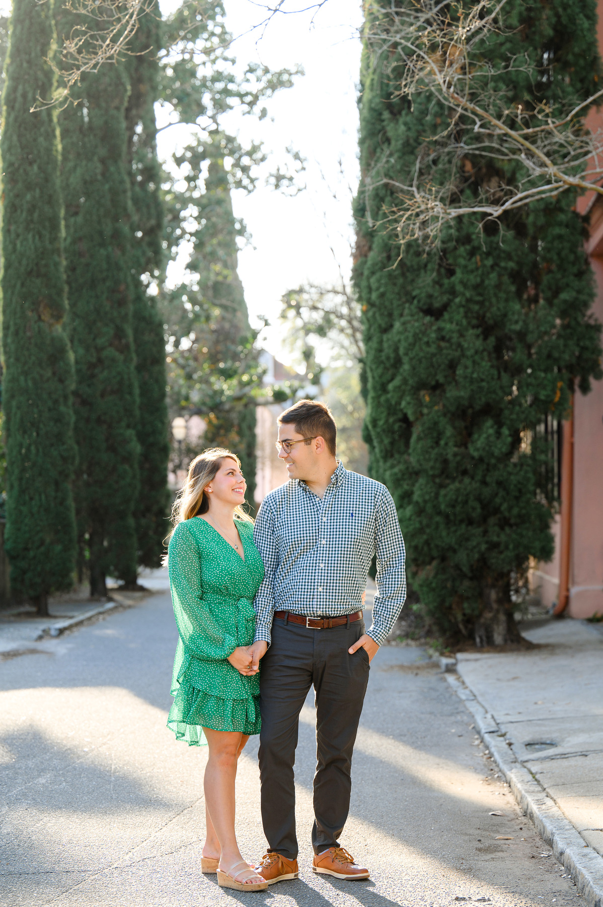 A woman in a green dress and a man in a plaid shirt and navy blue pants talk during their Charleston engagement photography session