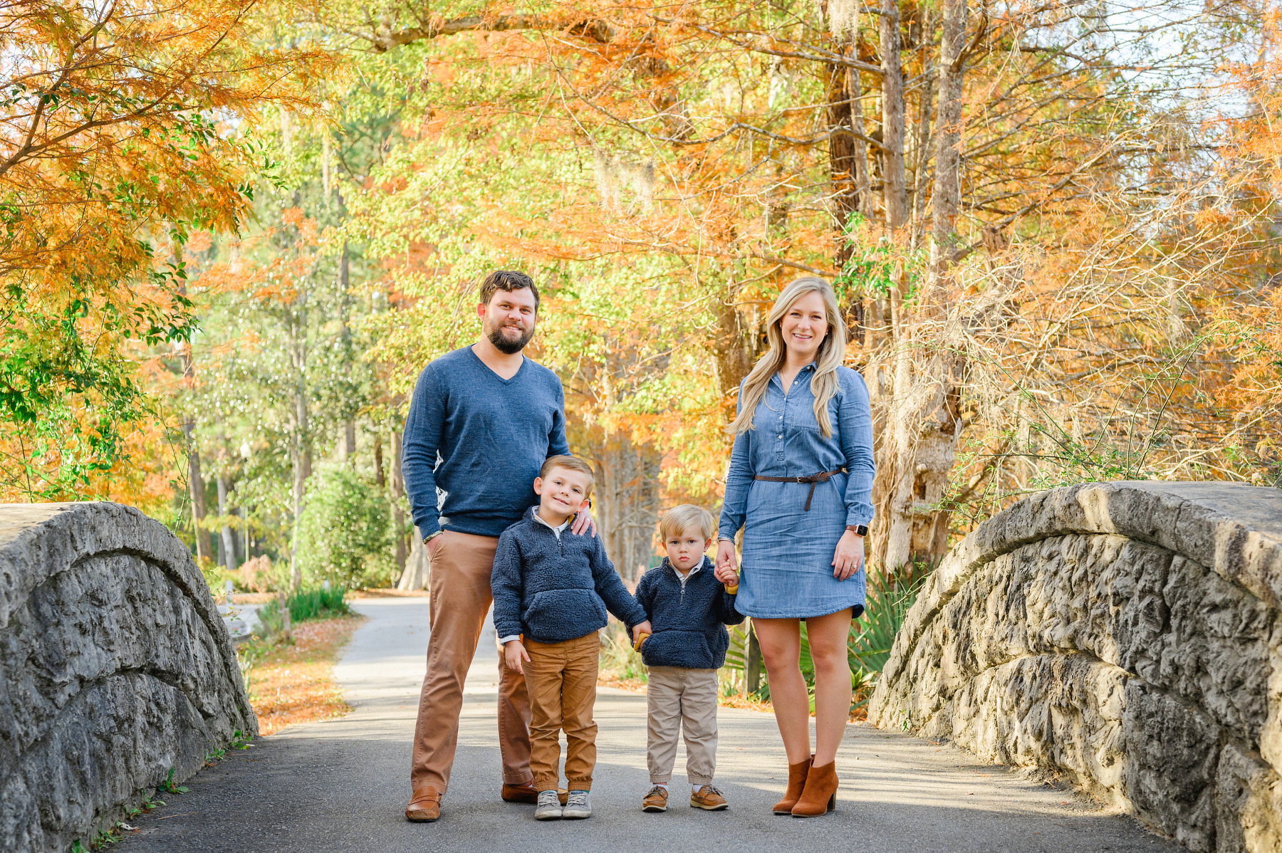 Fall Cypress Gardens Family photo session portrait of a dad, mom, and two young boys on a bridge dressed in shades of blue