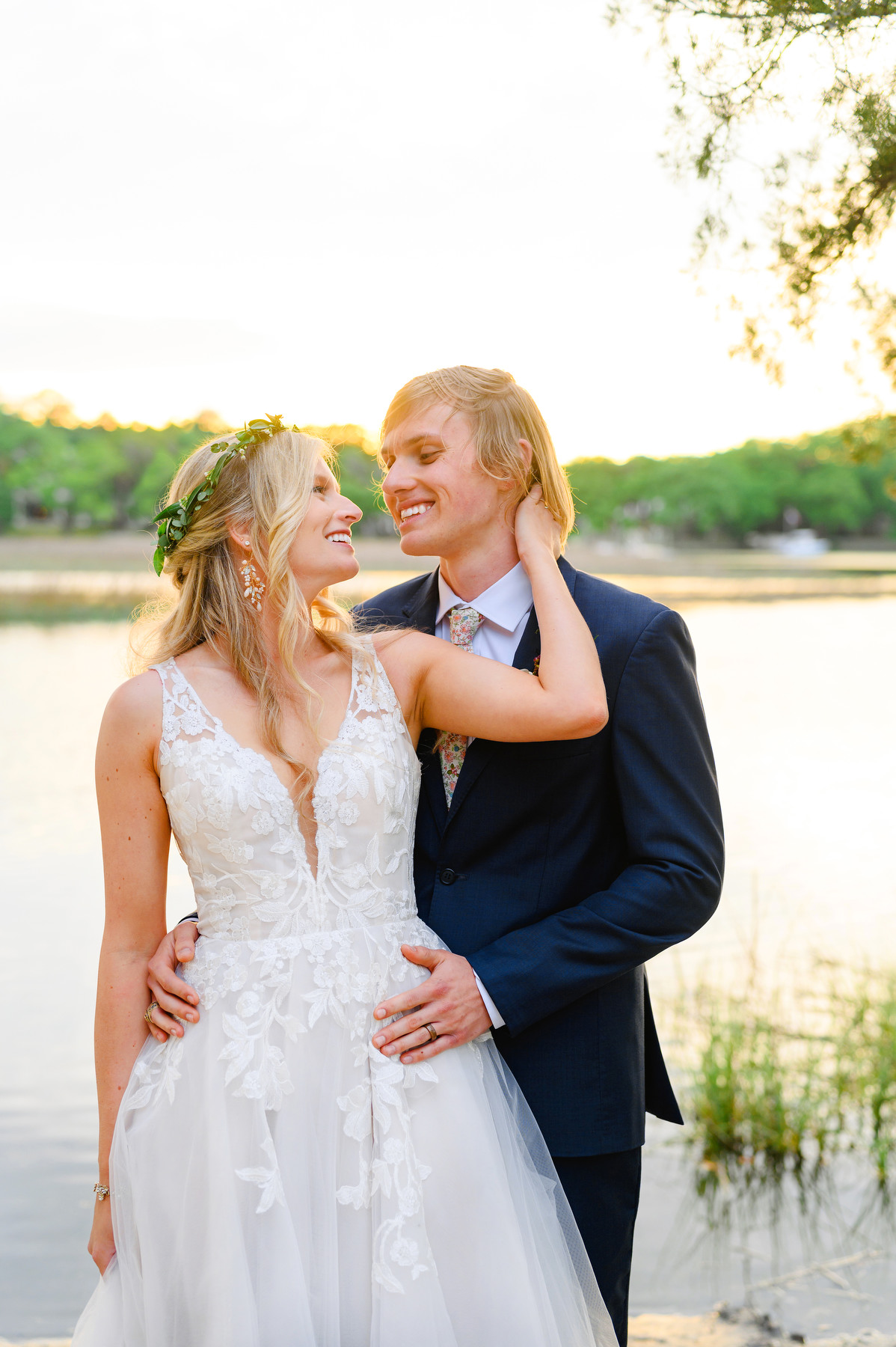 Portrait from a Cotton Dock wedding of the bride with a flower crown and white sleeveless dress with the groom in a blue suit