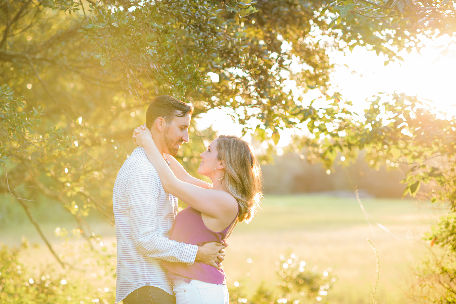 Hampton Park engagement photos portrait with a man dressed in a white long-sleeved shirt and a woman dressed in a fuschia tank top and white jeans.