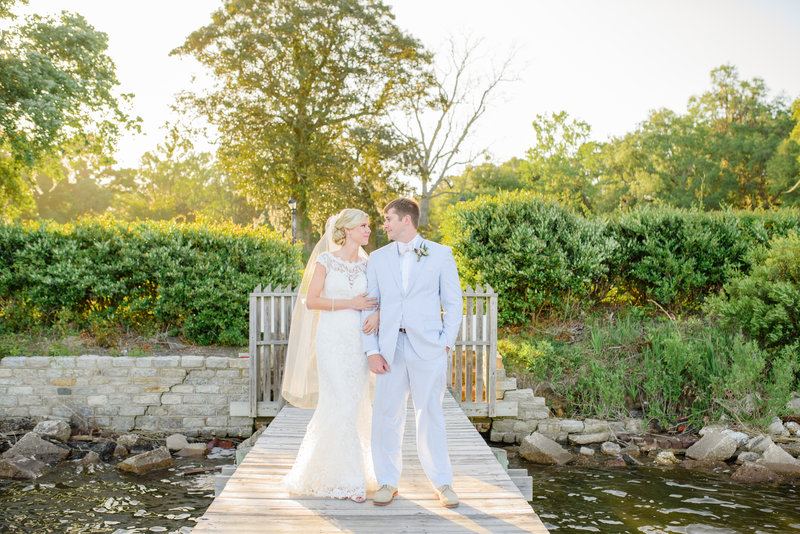 A bride and groom pose for a portrait by water after their Old Wide Awake wedding ceremony