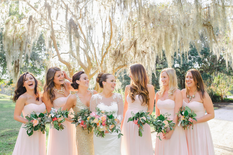 A bride in a white dress poses with her bridesmaids in blush pink dresses before an Upstairs at Midtown wedding