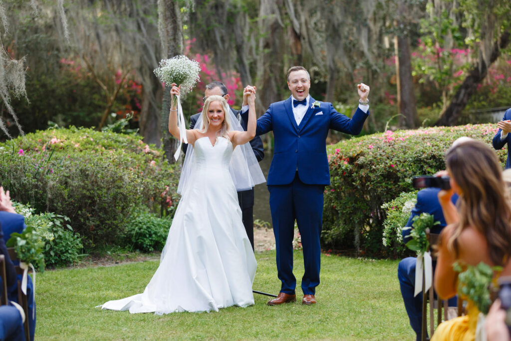 Bride and groom cheer after their first kiss as wife and husband at their al fresco Veranda Magnolia Plantation wedding.