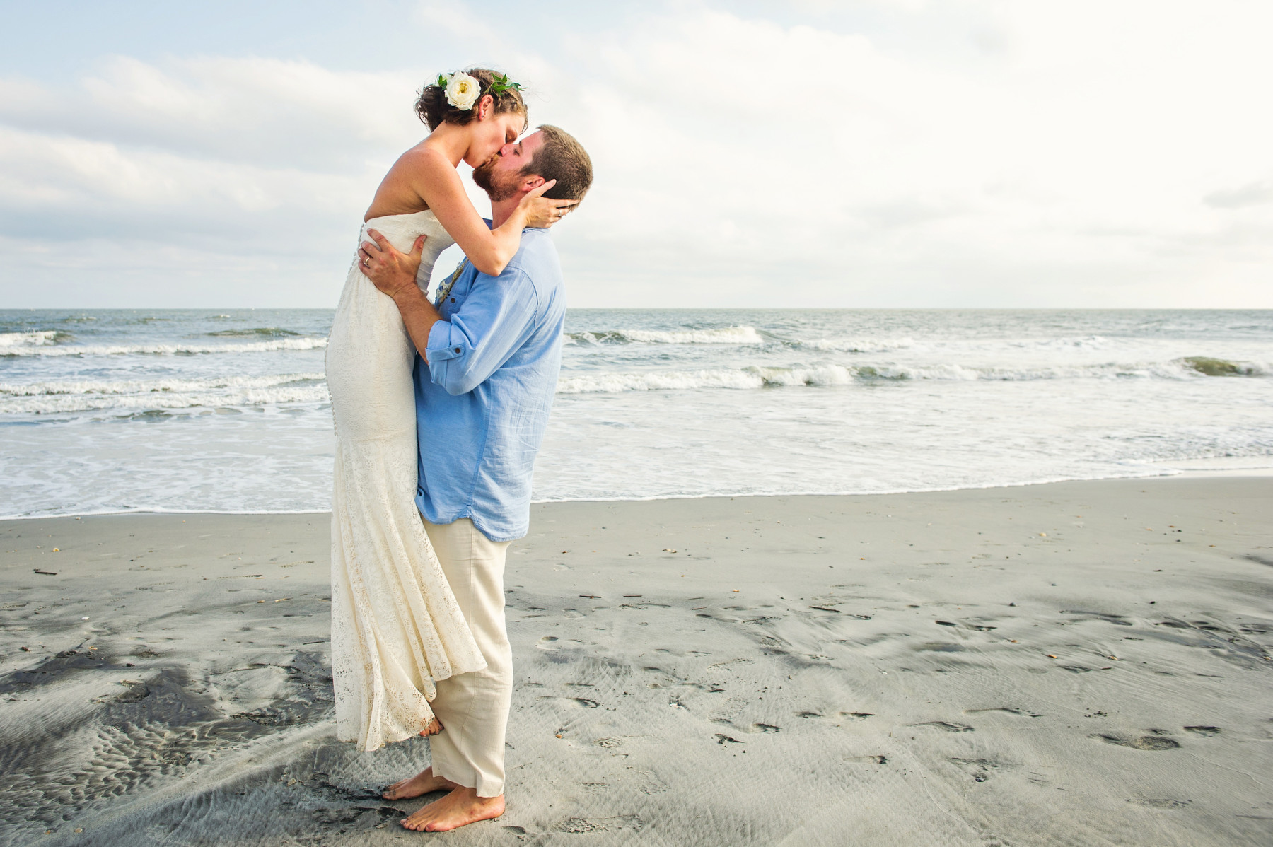 Bride and groom kiss on Isle of Palms beach before heading to their Citadel Beach Club wedding reception.