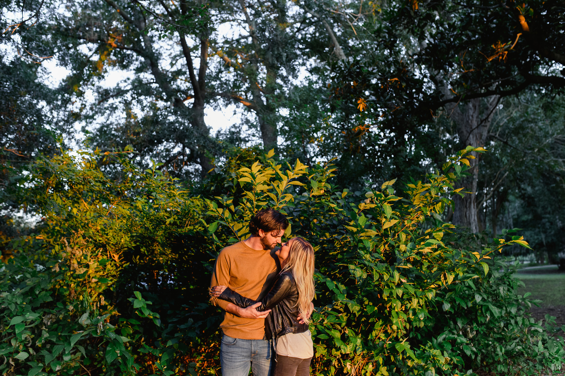 A man and woman hold each other for a portrait during a fall Hampton Park engagement photos session in Charleston, SC