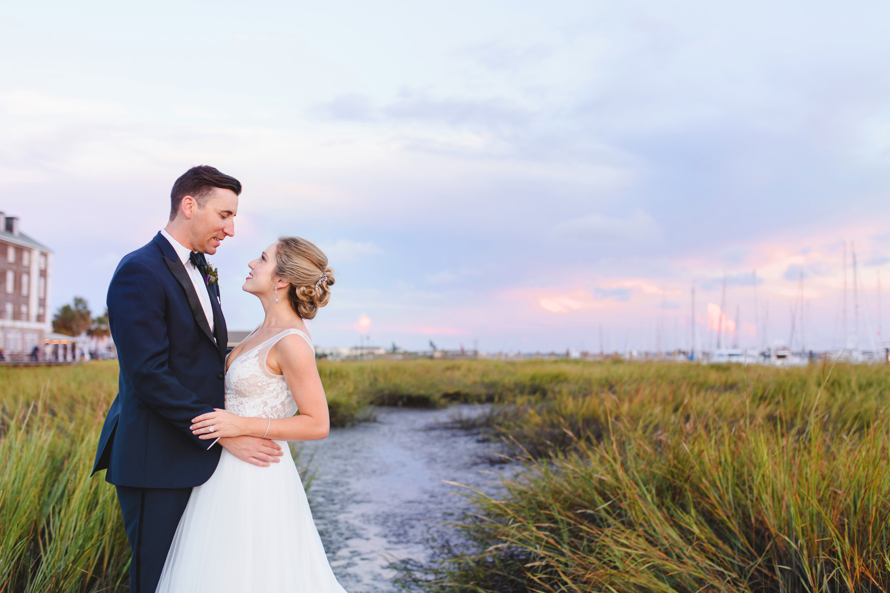 A bride and groom pose for a portrait on a pier during their Historic Rice Mill wedding reception in Charleston, SC.