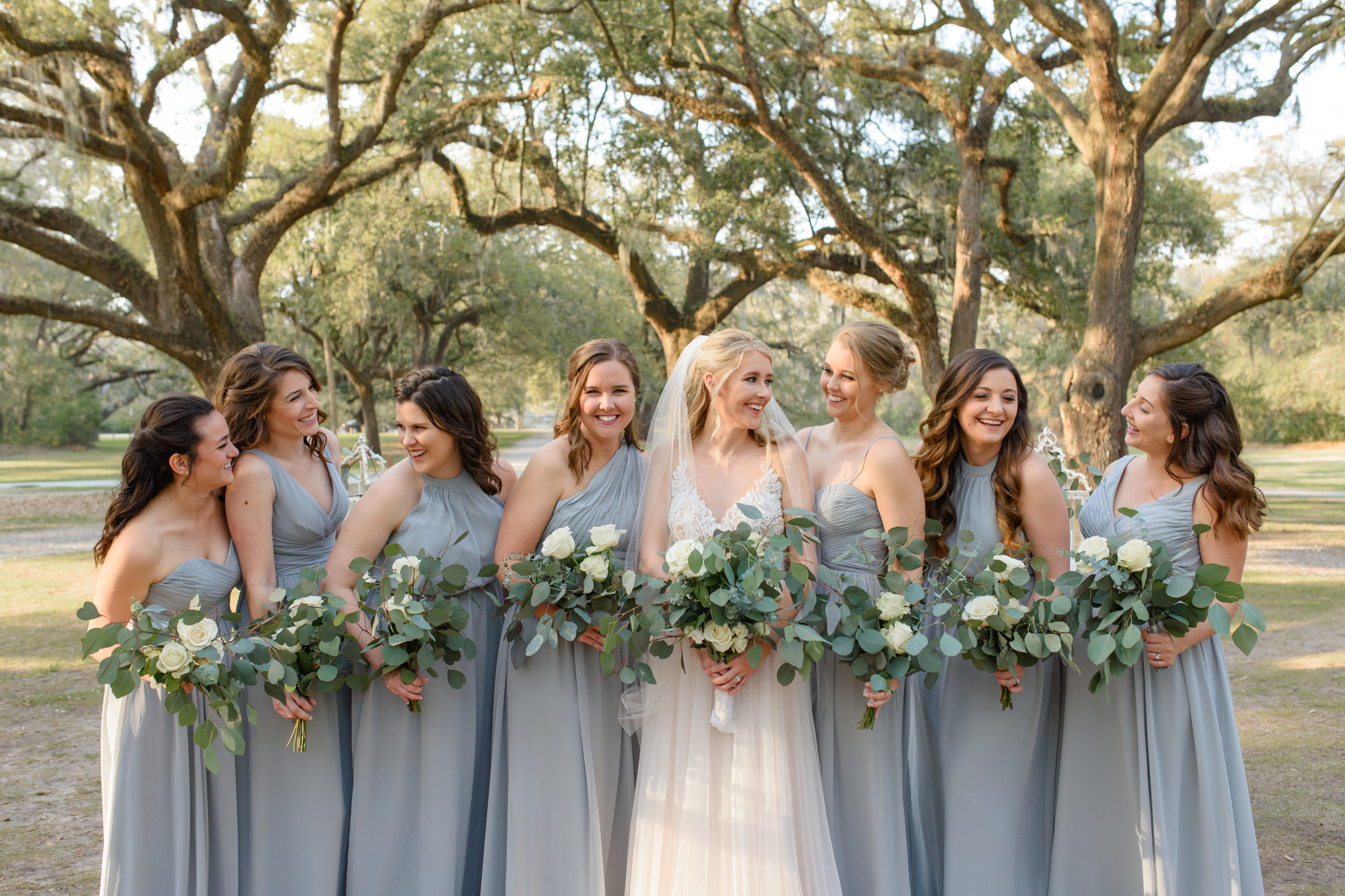 A bride and her bridesmaids laugh during portraits at a McLeod Plantation wedding