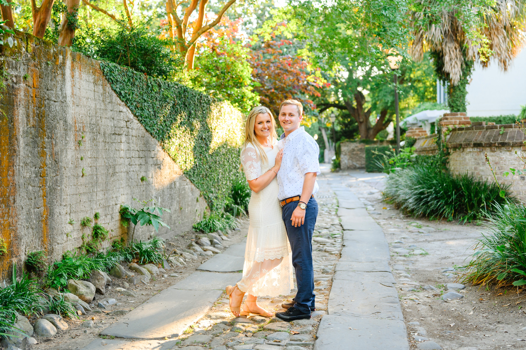 A woman and man pose during their spring Rainbow Row engagement session.