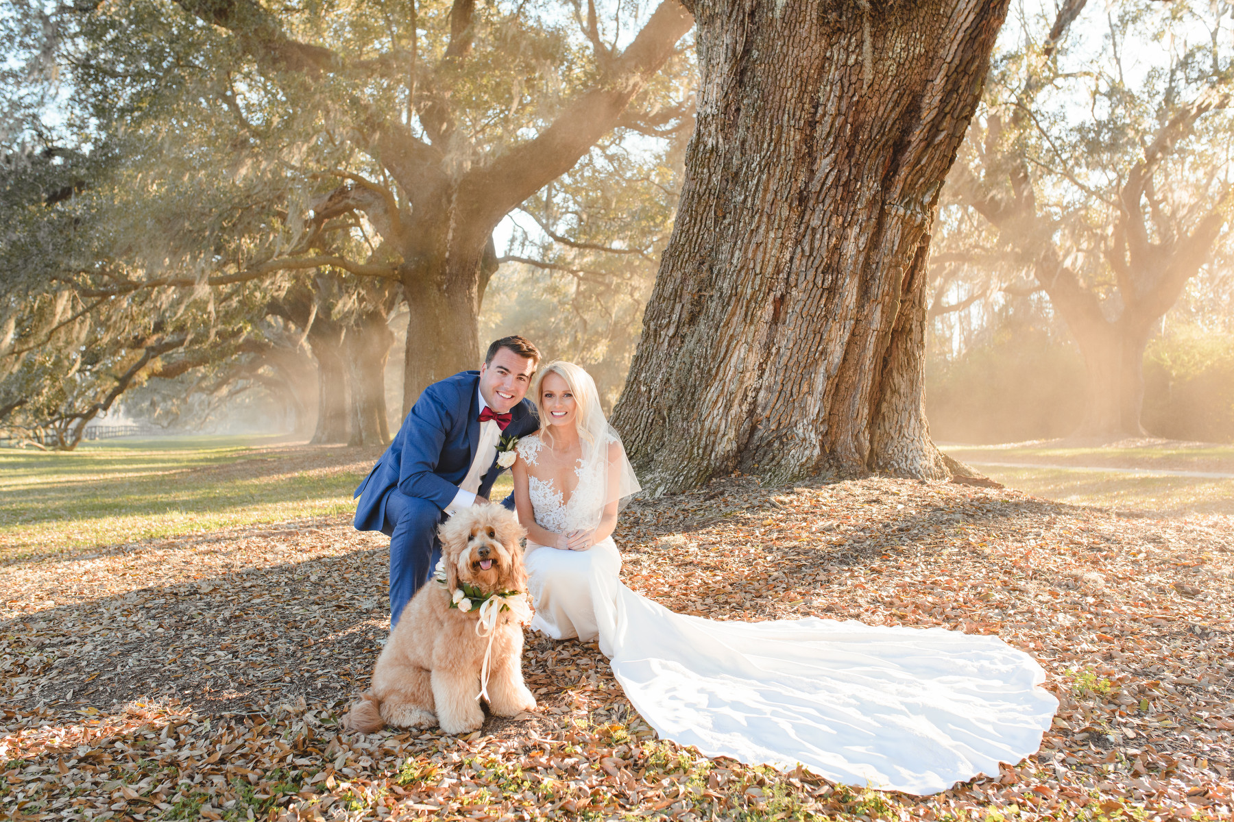 A groom and a bride pose with their dog at their winter Cotton Dock wedding at Boone Hall.